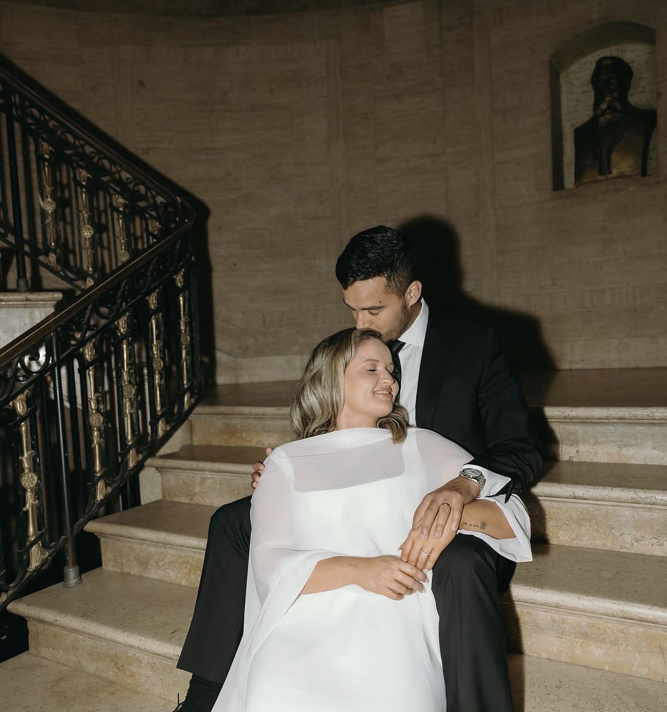 Matheus and Layza seated together on a grand staircase, elegant and close