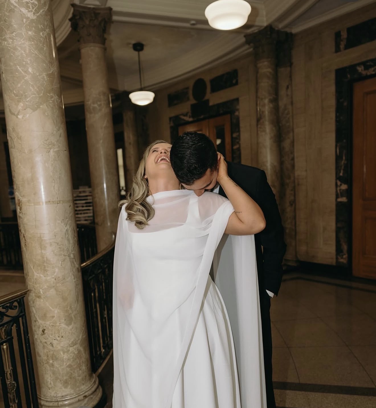Layza laughing as Matheus holds her close among the columns