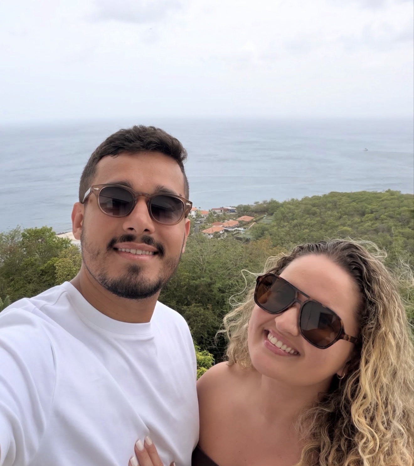 The couple smiling on a hilltop above the Caribbean coast