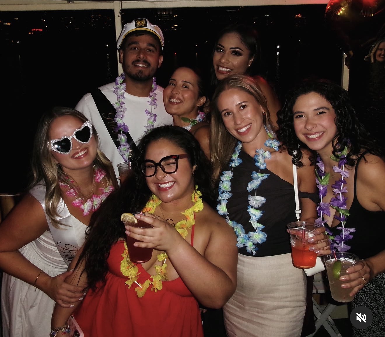 The bride and friends laughing with drinks on the boat deck