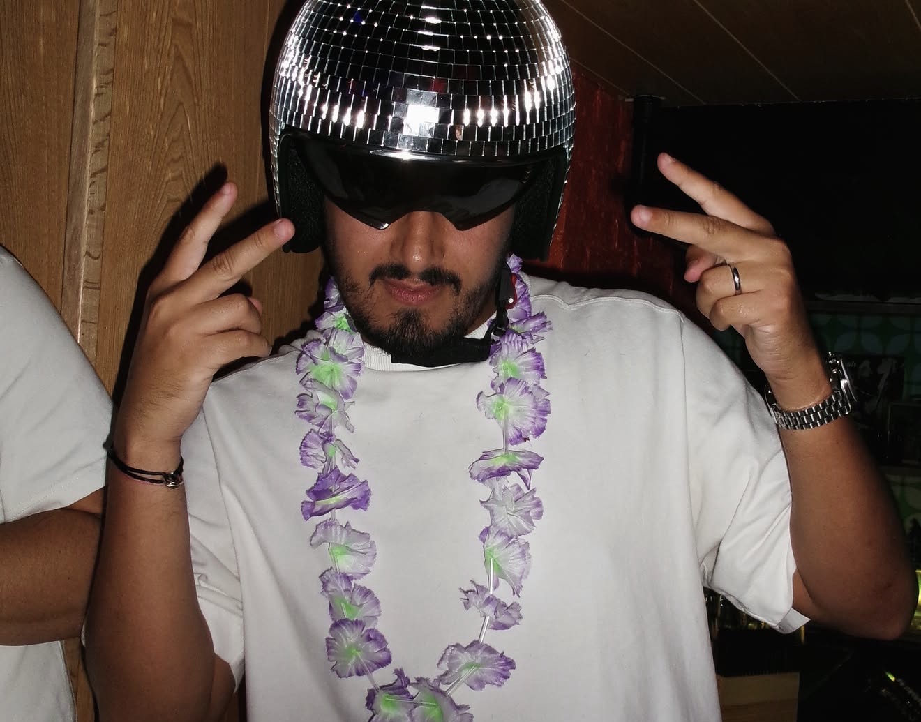 Matheus wearing a disco-ball helmet and a flower lei