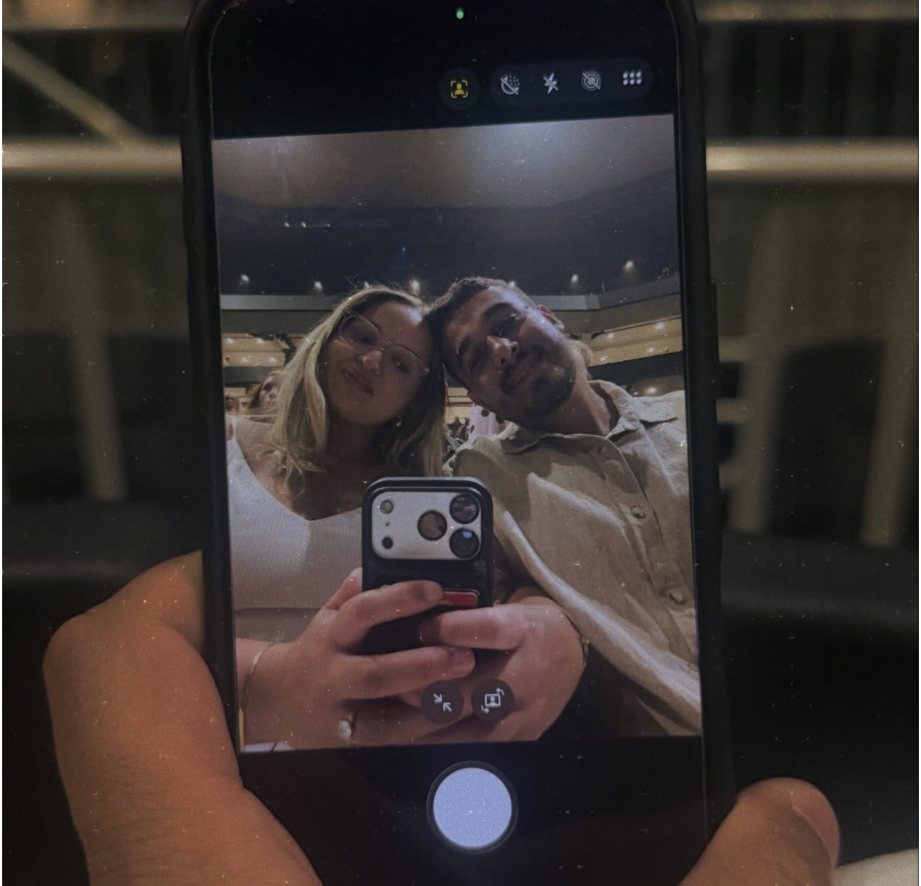 A phone screen selfie of the couple leaning head to head