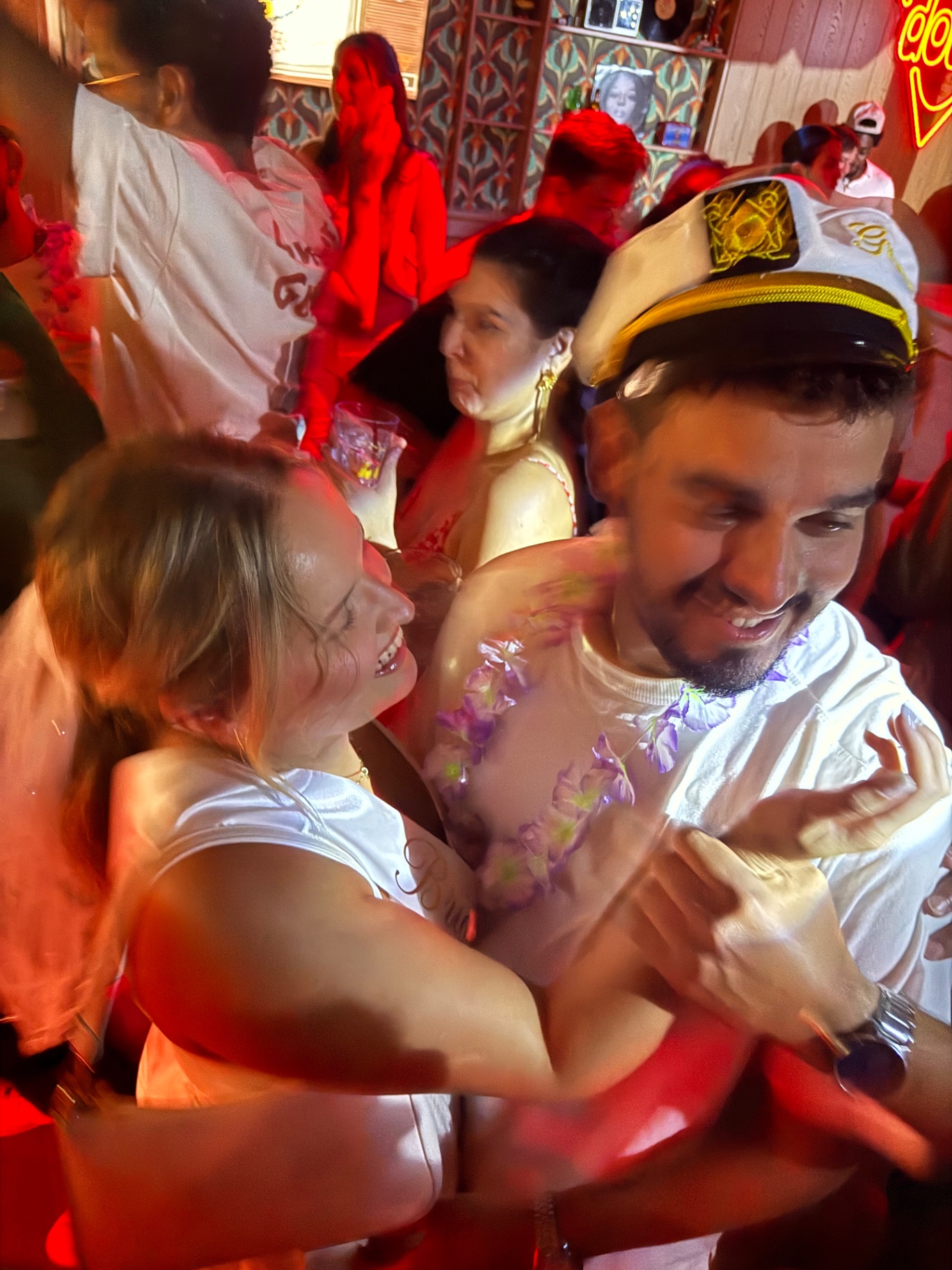 The couple laughing in the middle of the crowd under red lights