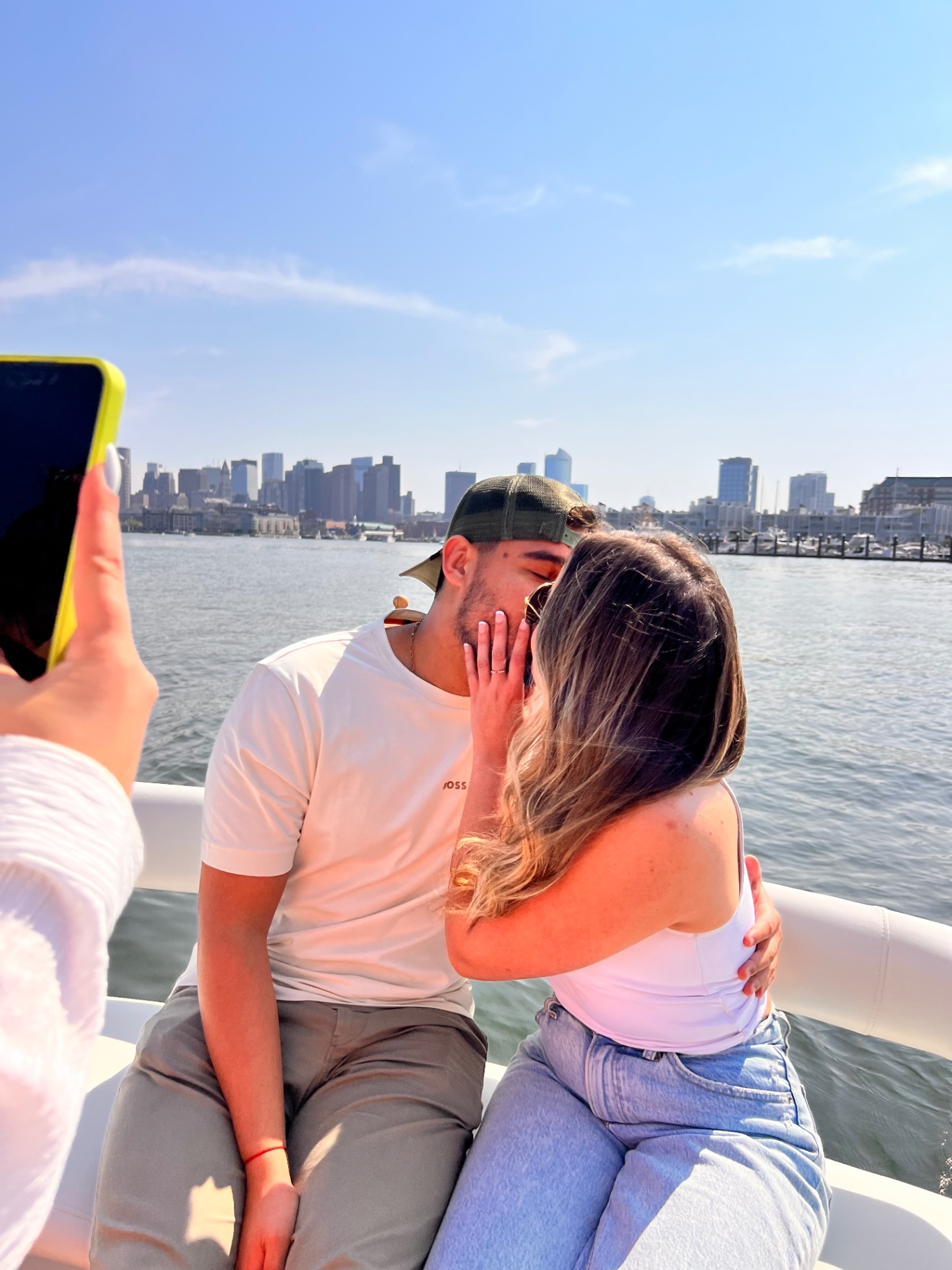 The couple kissing on the boat as the city glows behind them